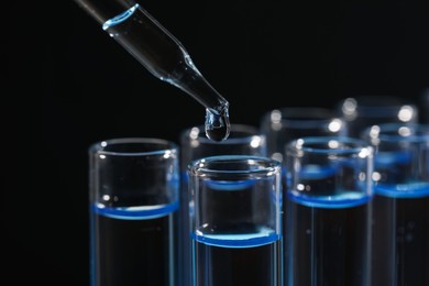 Photo of Dripping reagent into test tube on black background, closeup. Laboratory analysis