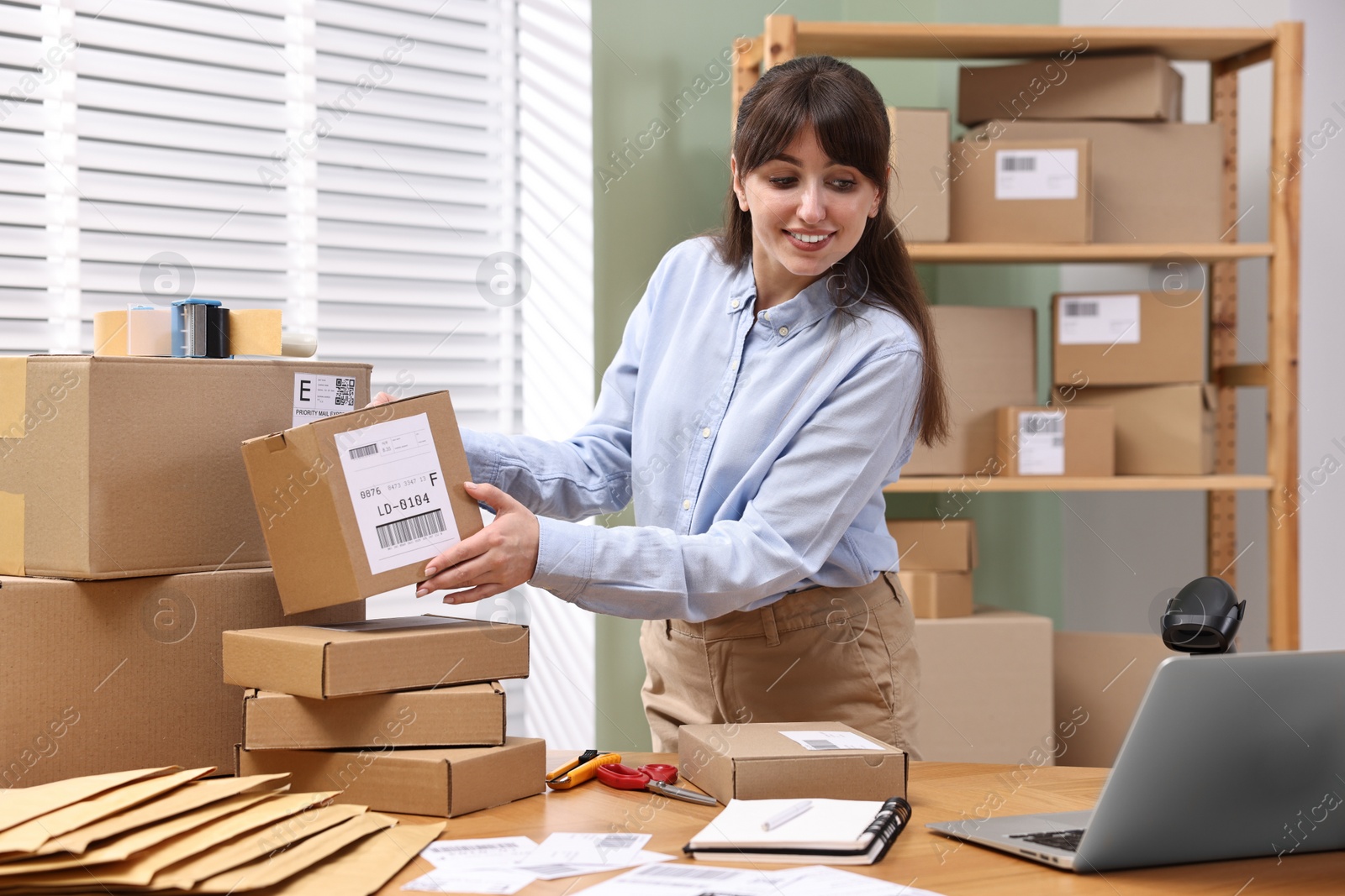 Photo of Parcel packing. Post office with parcels at wooden table indoors