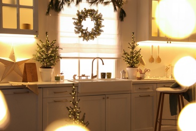 Photo of Small Christmas trees and festive decor in kitchen