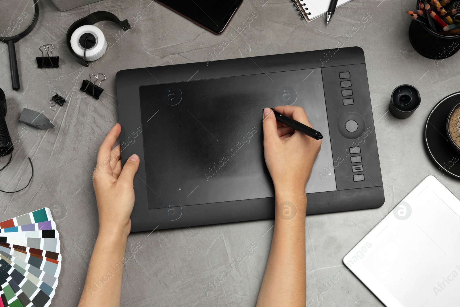 Photo of Professional designer drawing with graphic tablet at grey stone table, top view
