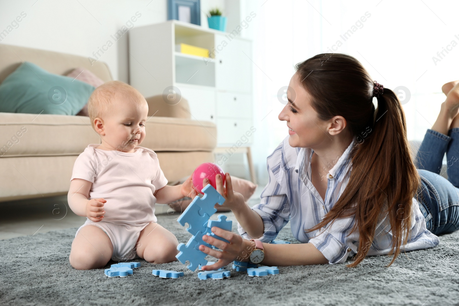 Photo of Happy mother playing with little baby on floor indoors