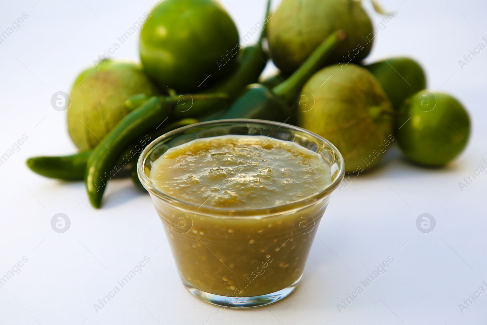 Photo of Bowl with delicious salsa sauce and ingredients on white background, closeup