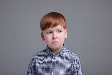 Portrait of sad little boy on grey background