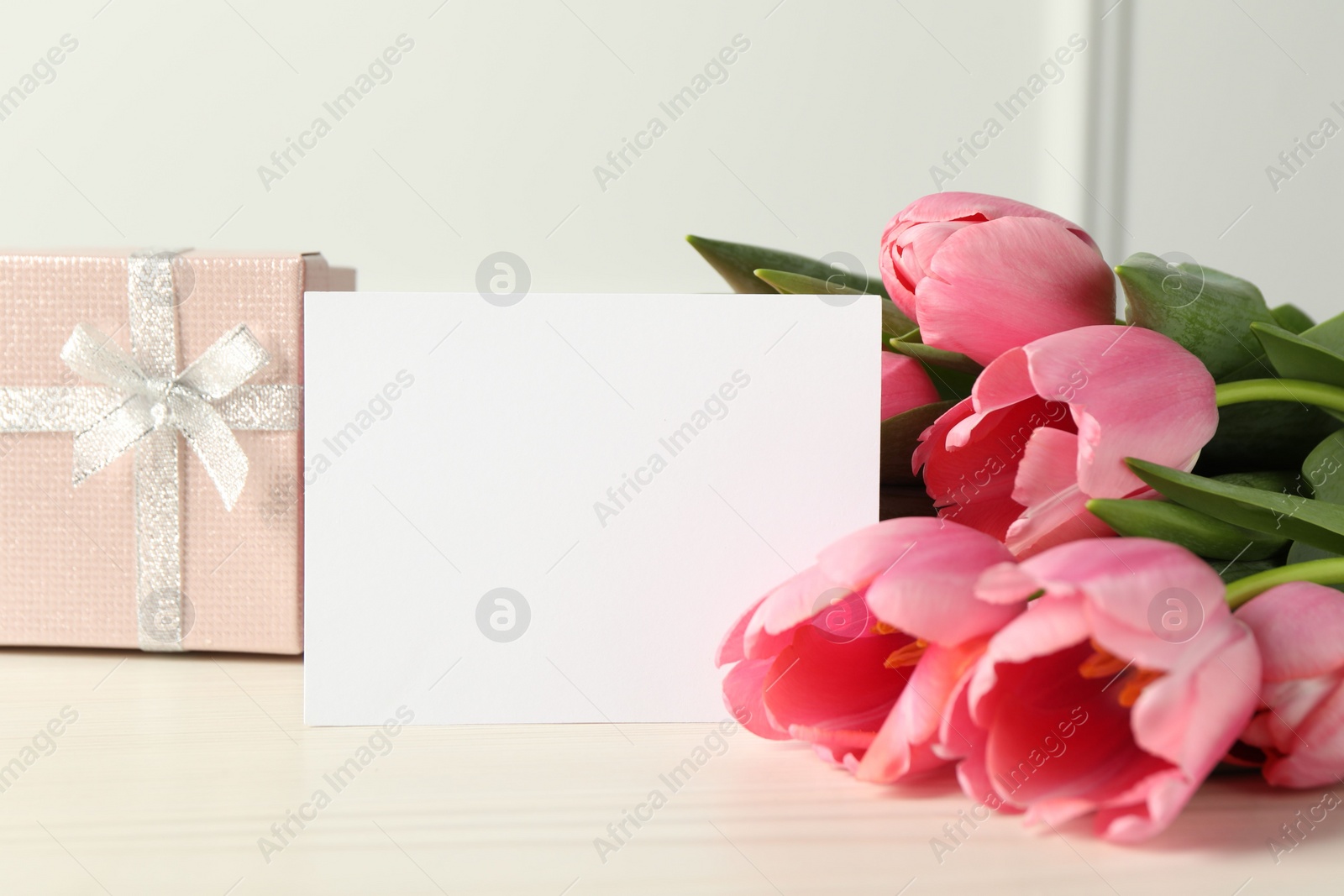 Photo of Happy Mother's Day. Beautiful tulips, gift box and blank card on white wooden table, closeup