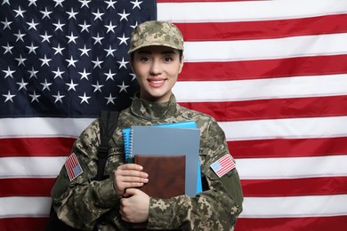 Photo of Female soldier with backpack and notebooks near flag of United States. Military education