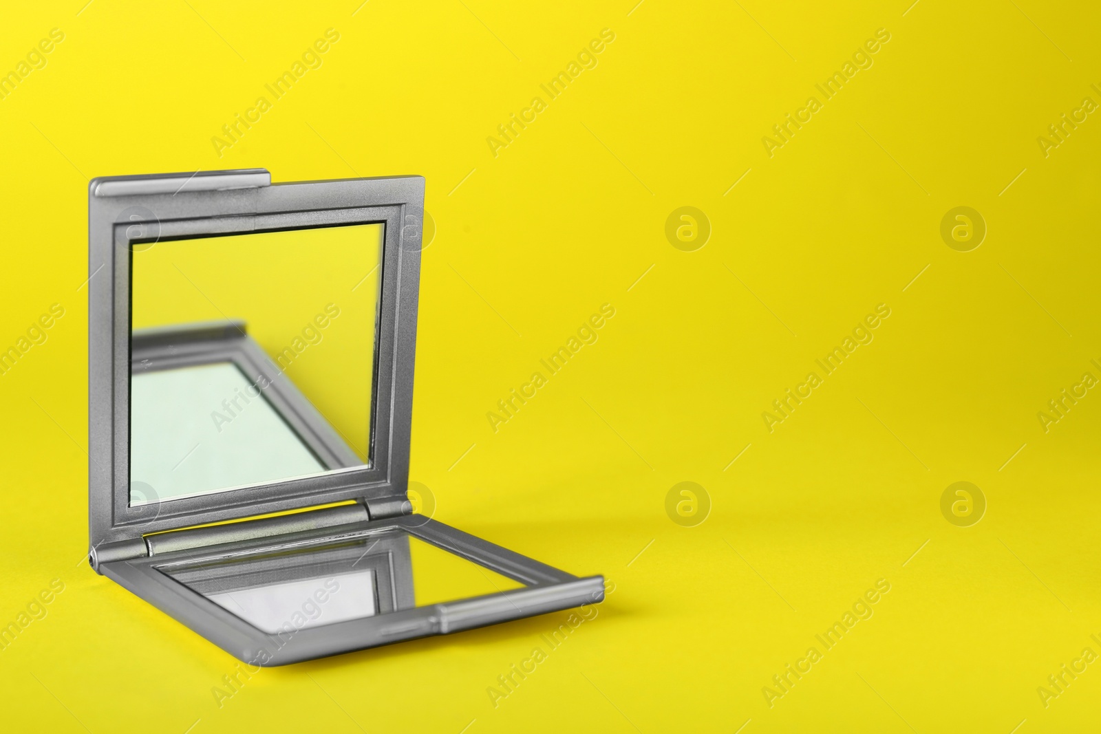 Photo of Stylish cosmetic pocket mirror on yellow background. Space for text