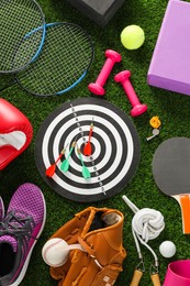 Photo of Different sport equipment on green grass, flat lay