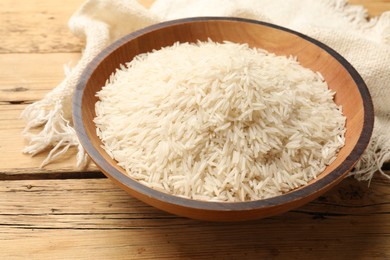 Photo of Raw basmati rice in bowl on wooden table