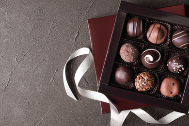 Box with tasty chocolate candies on black table, flat lay