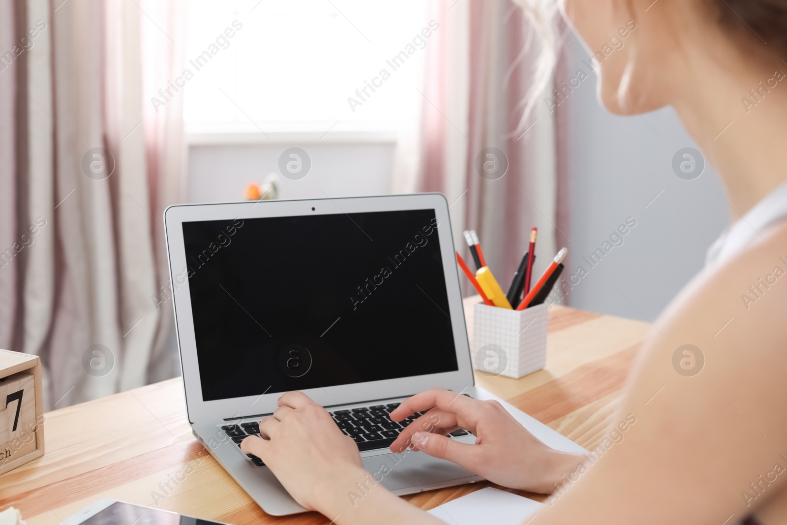 Photo of Young woman working with laptop at desk. Home office