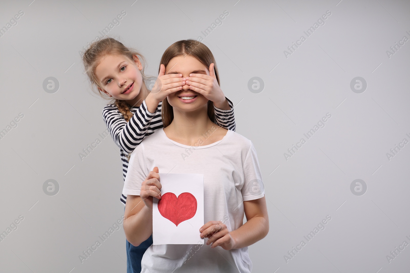 Photo of Little daughter congratulating her mom with postcard on white background, space for text. Happy Mother's Day