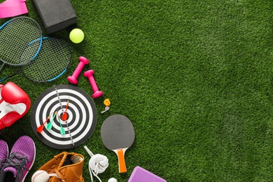 Photo of Different sport equipment on green grass, flat lay. Space for text