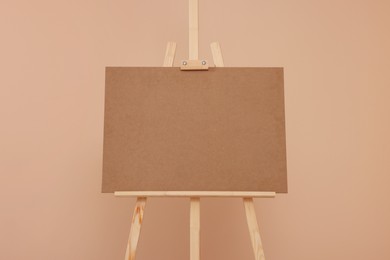 Wooden easel with blank board on beige background