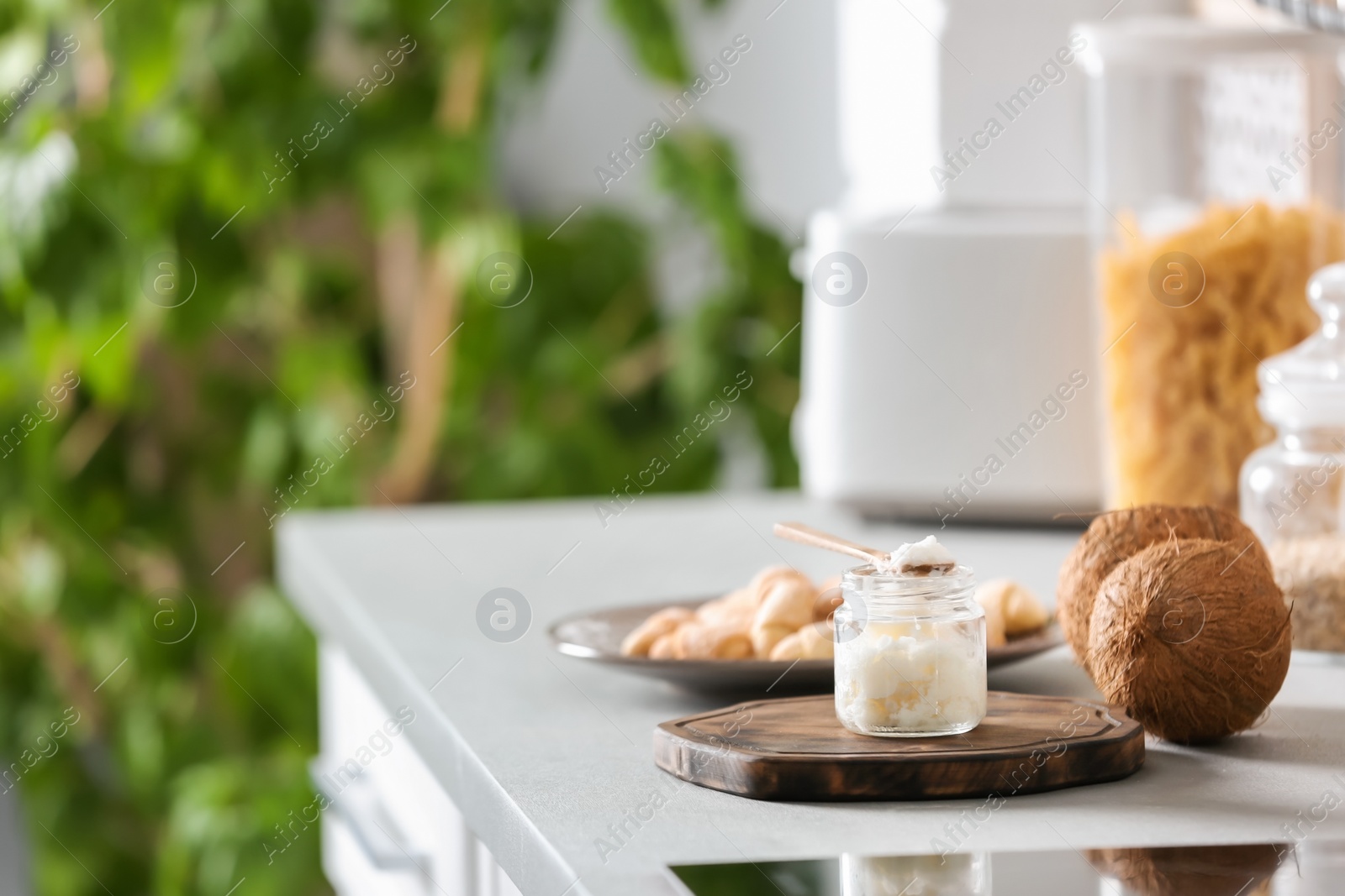 Photo of Jar with coconut oil on table in kitchen. Healthy cooking