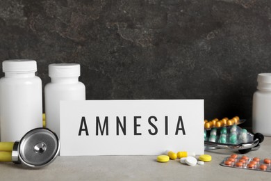 Photo of Card with word Amnesia, drugs and stethoscope on light grey table