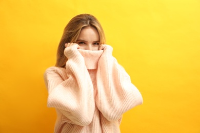 Photo of Beautiful young woman wearing knitted sweater on yellow background