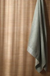 Soft towel hanging on bamboo wall indoors, space for text