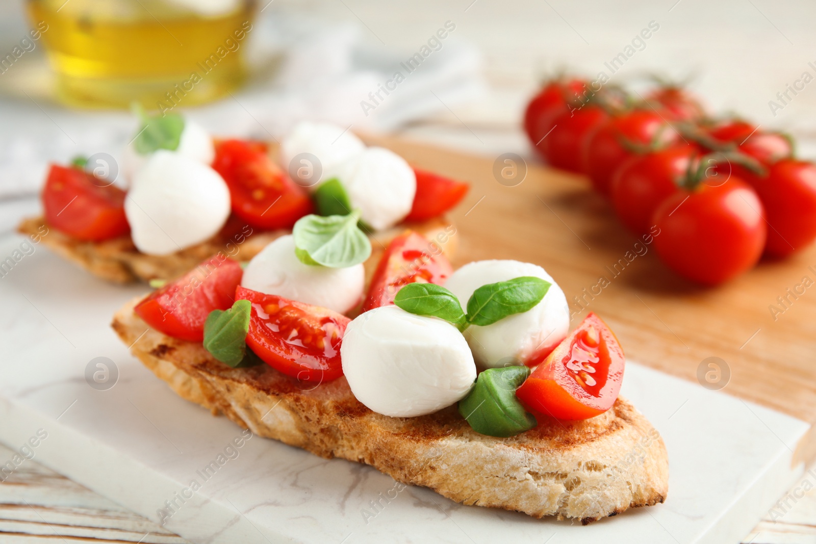 Photo of Delicious sandwich with mozzarella, fresh tomatoes and basil on board