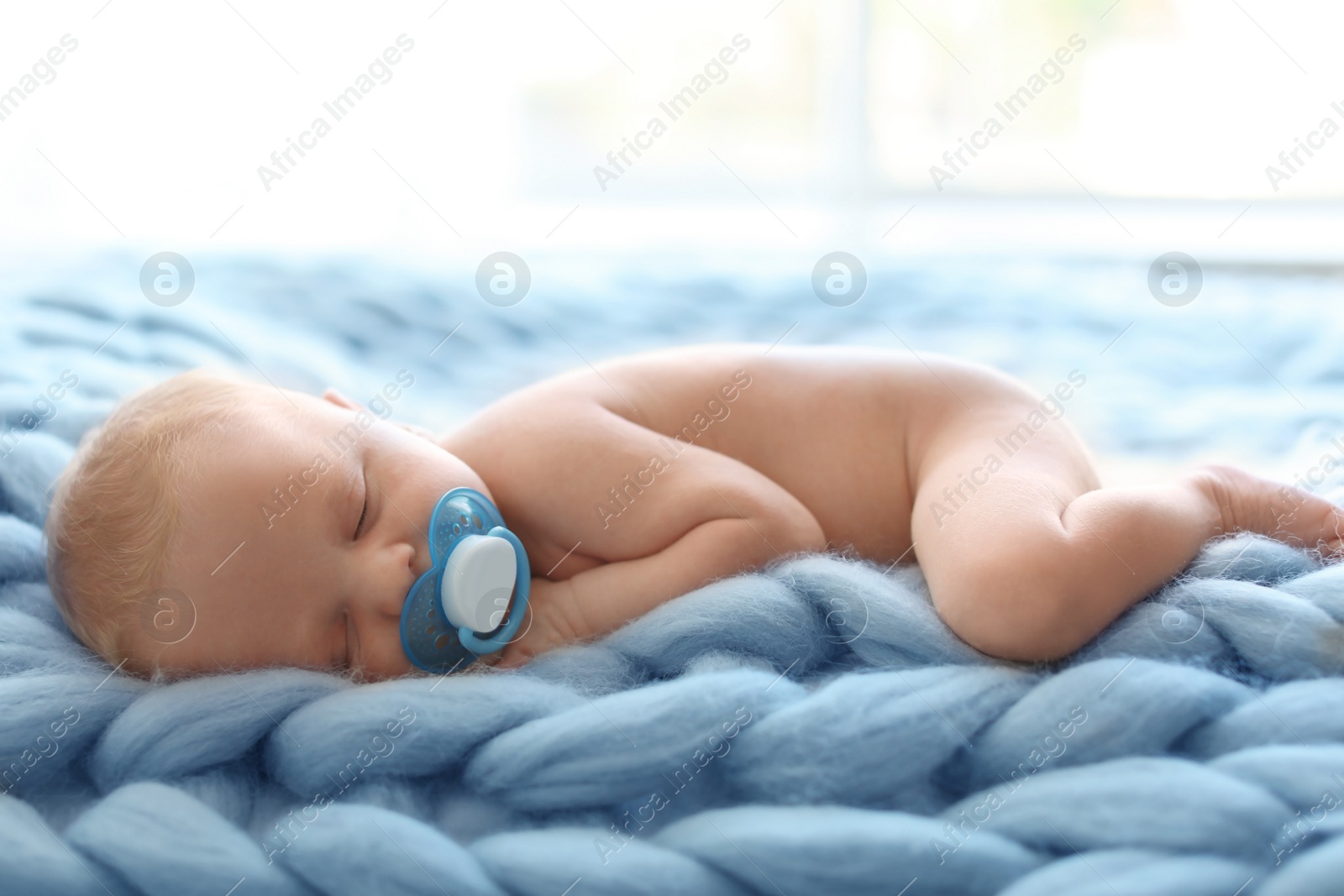 Photo of Adorable newborn baby lying on knitted blanket indoors