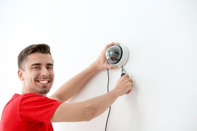 Photo of Technician installing CCTV camera on wall indoors