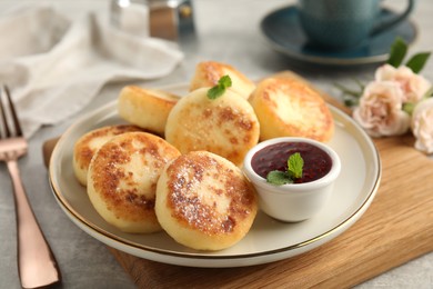 Delicious cottage cheese pancakes with jam, mint and icing sugar on grey table