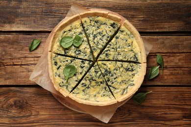 Photo of Cut delicious spinach pie on wooden table, top view