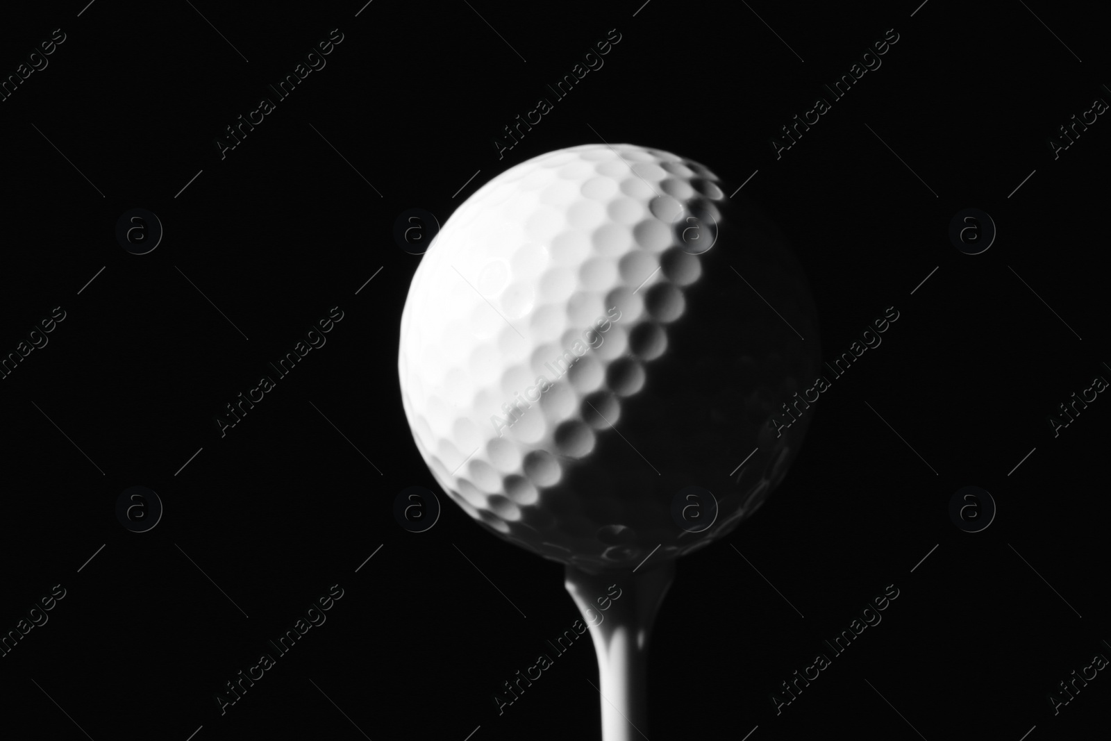 Photo of Golf ball on tee against dark background