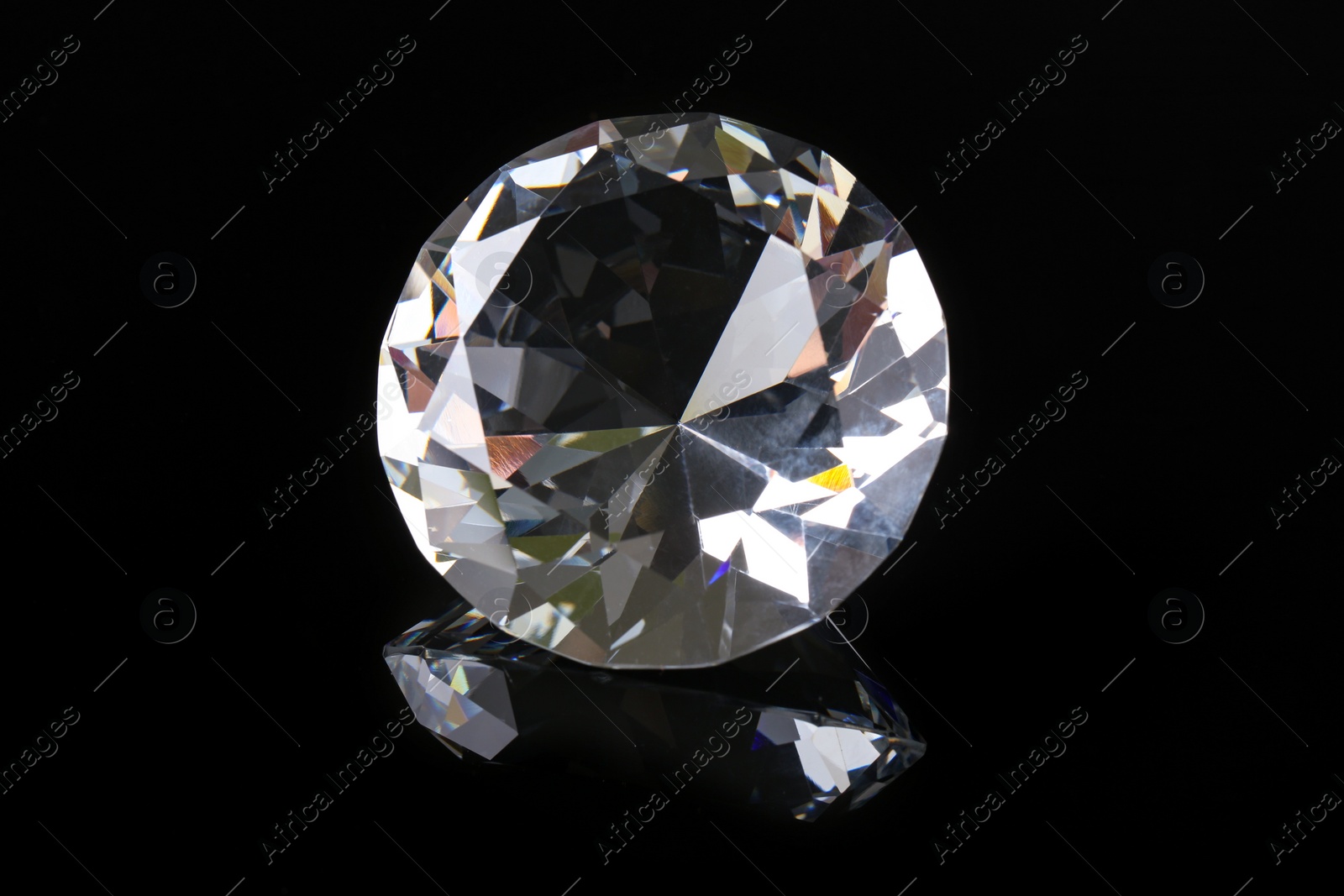 Photo of Beautiful shiny diamond on black mirror surface, closeup
