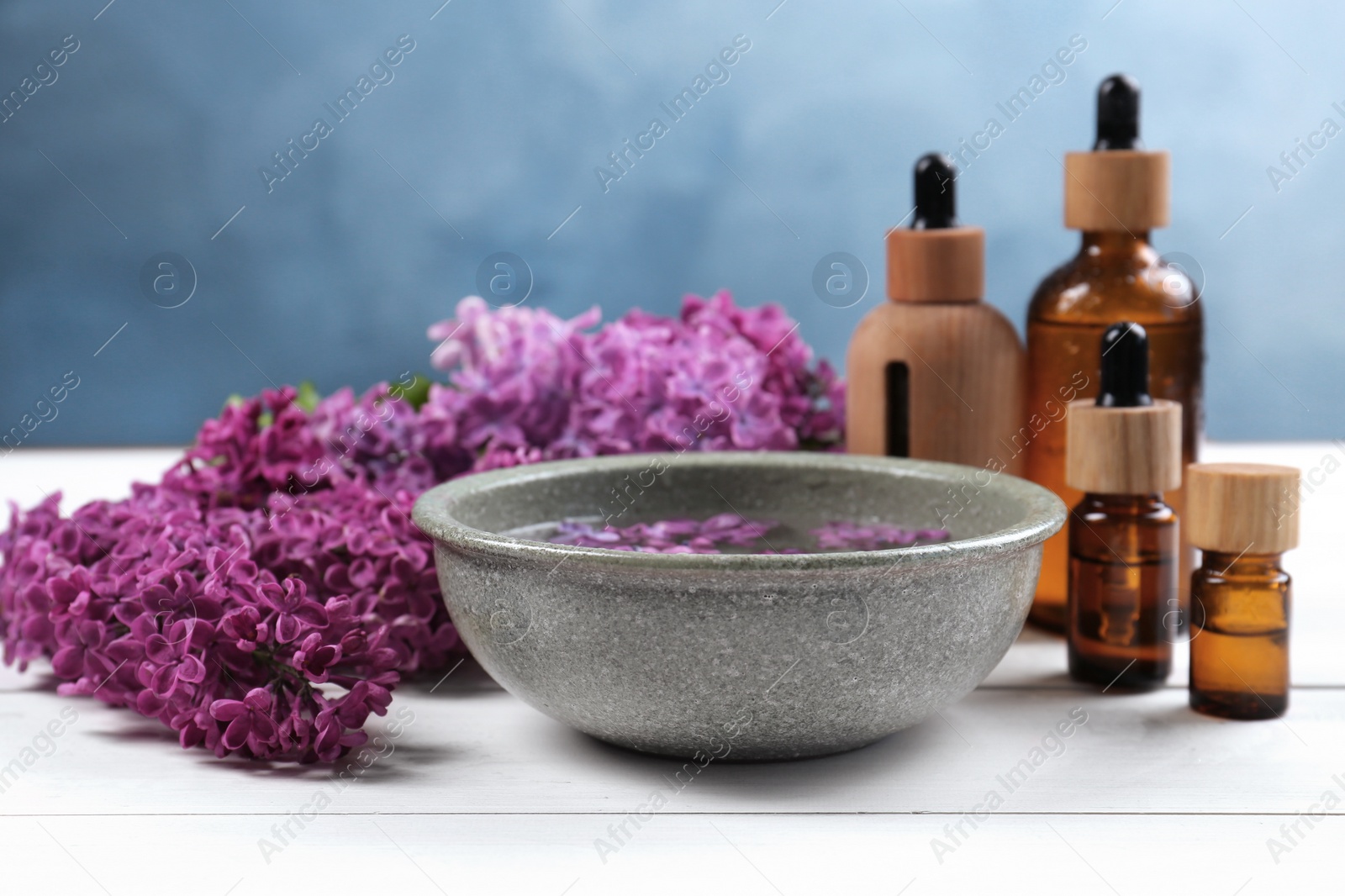 Photo of Cosmetic products and lilac flowers on white wooden table