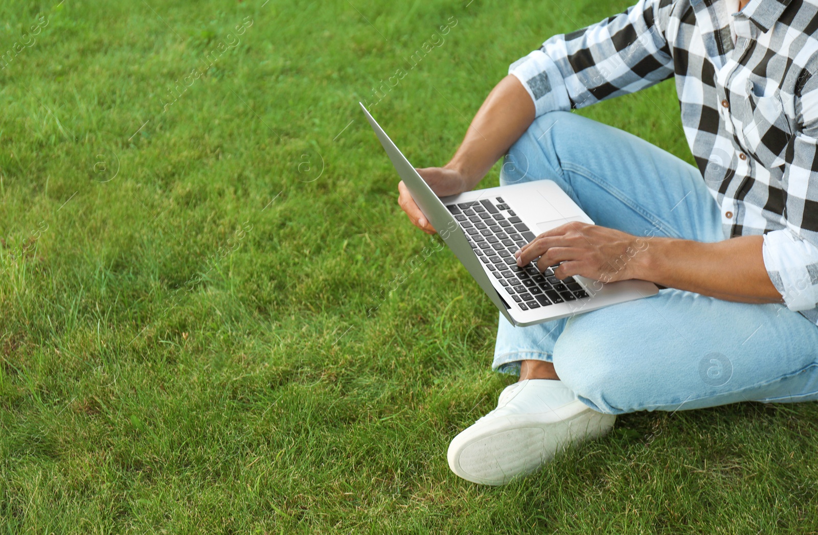 Photo of Young man working on laptop outdoors, closeup. Space for text