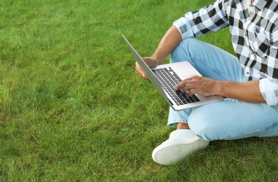Photo of Young man working on laptop outdoors, closeup. Space for text