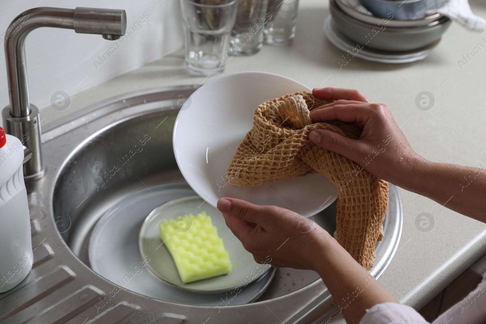 Photo of Woman wiping plate with towel in kitchen , closeup