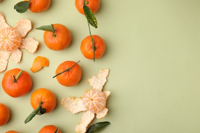 Photo of Many fresh ripe tangerines and leaves on light green table, flat lay. Space for text