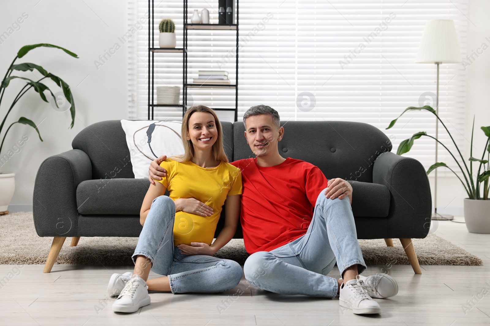 Photo of Young family housing concept. Pregnant woman with her husband on floor at home