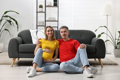 Young family housing concept. Pregnant woman with her husband on floor at home