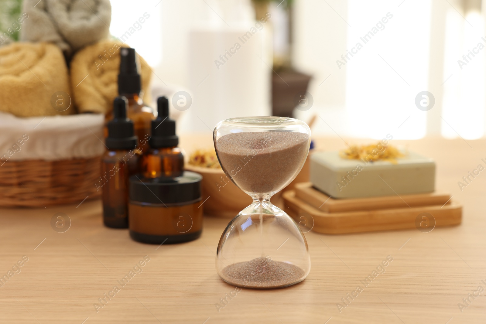 Photo of Sandglass on wooden table indoors. Spa time