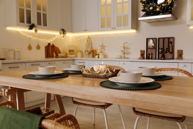 Photo of Table with dishware in beautiful kitchen decorated for Christmas. Interior design