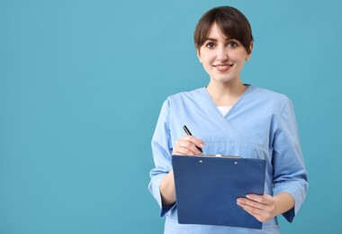 Portrait of smiling medical assistant with clipboard on light blue background