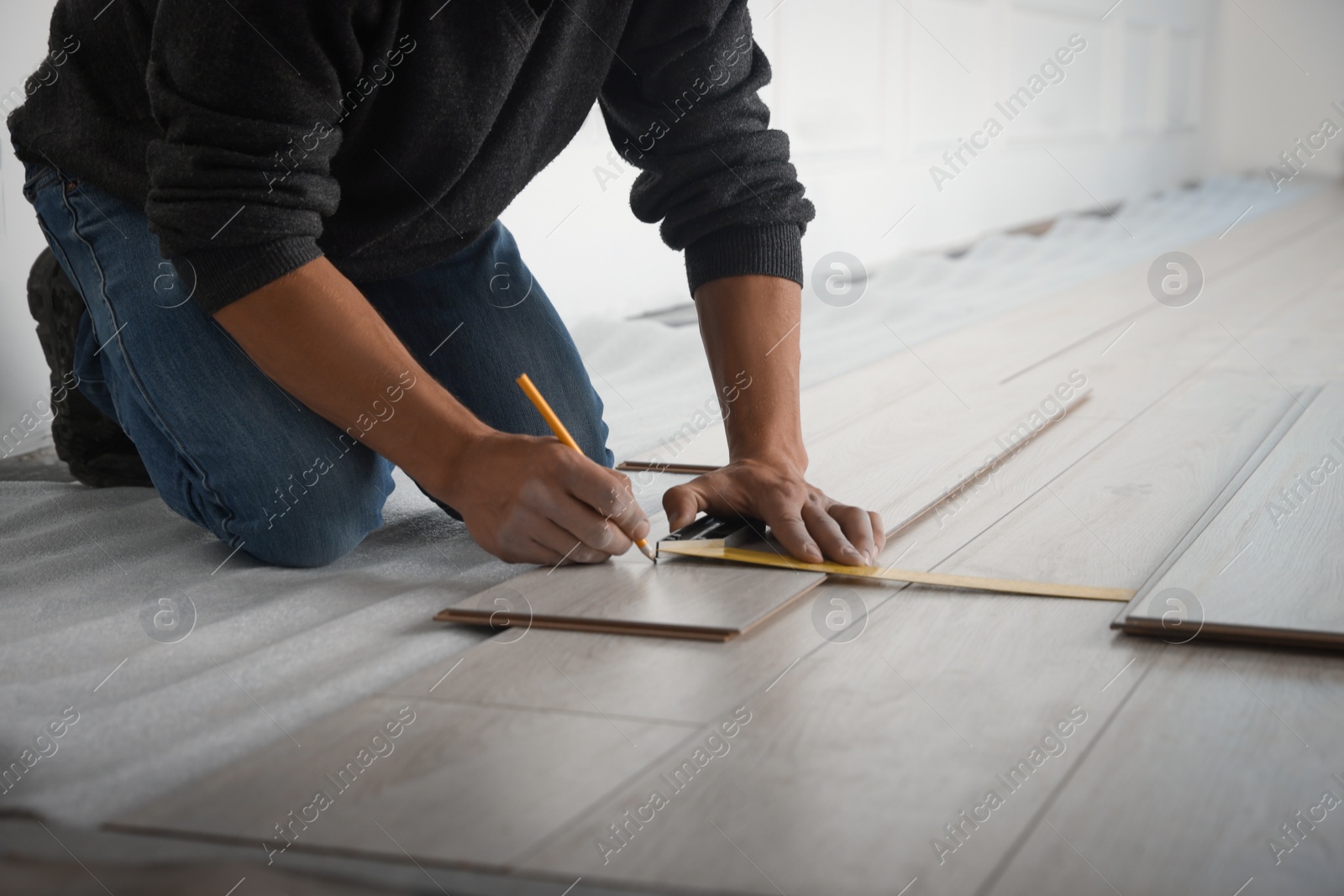 Photo of Worker installing new laminate flooring in room, closeup