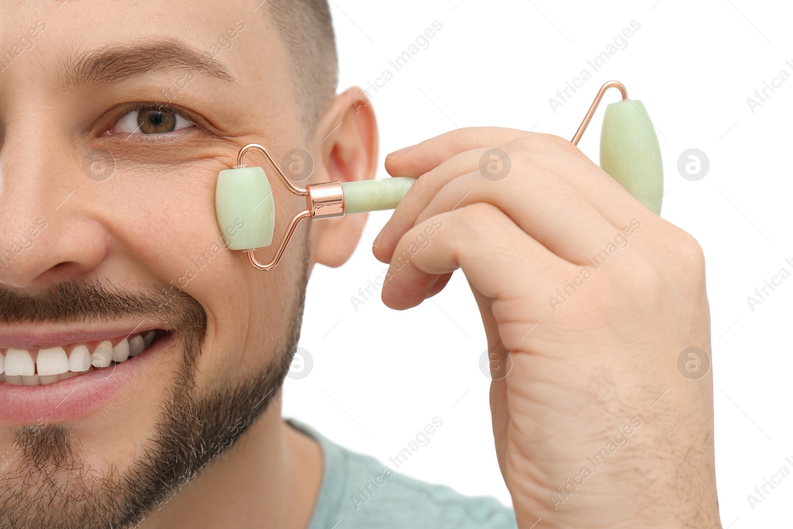 Photo of Man using nephrite facial roller on white background, closeup