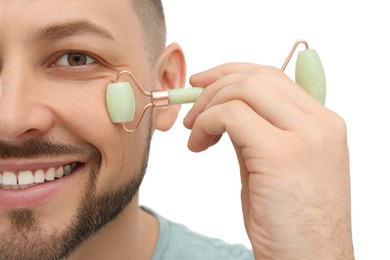 Man using nephrite facial roller on white background, closeup