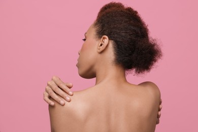 Beautiful young woman with stylish hairstyle on pink background, back view