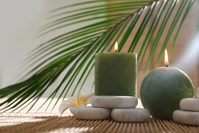 Photo of Composition with spa stones and candles on bamboo mat