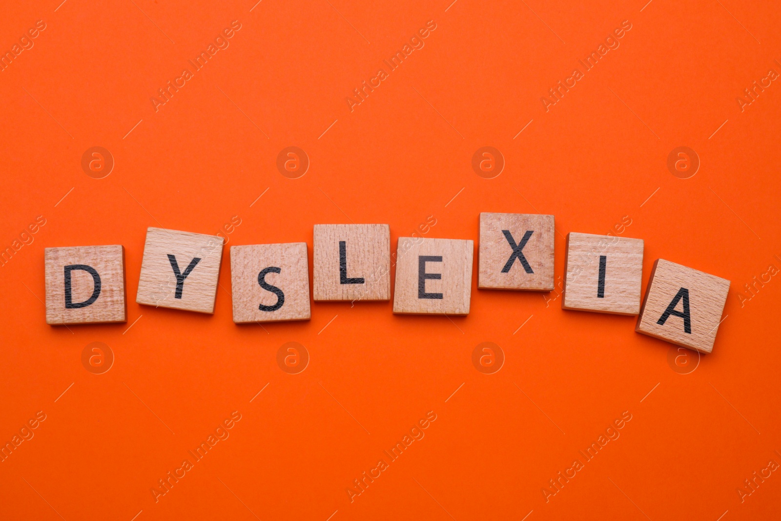 Photo of Wooden cubes with word Dyslexia on orange background, flat lay