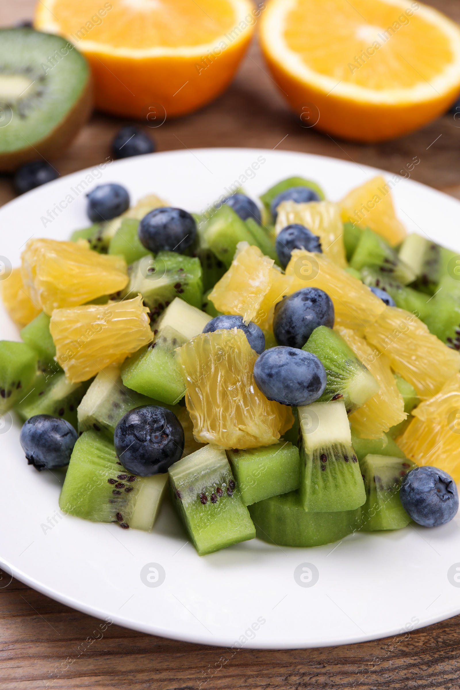 Photo of Plate of tasty fruit salad on wooden table, closeup