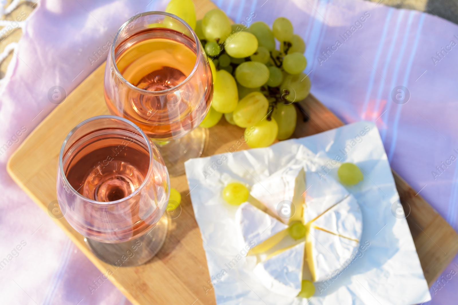 Photo of Glasses with rose wine and snacks on picnic blanket, above view