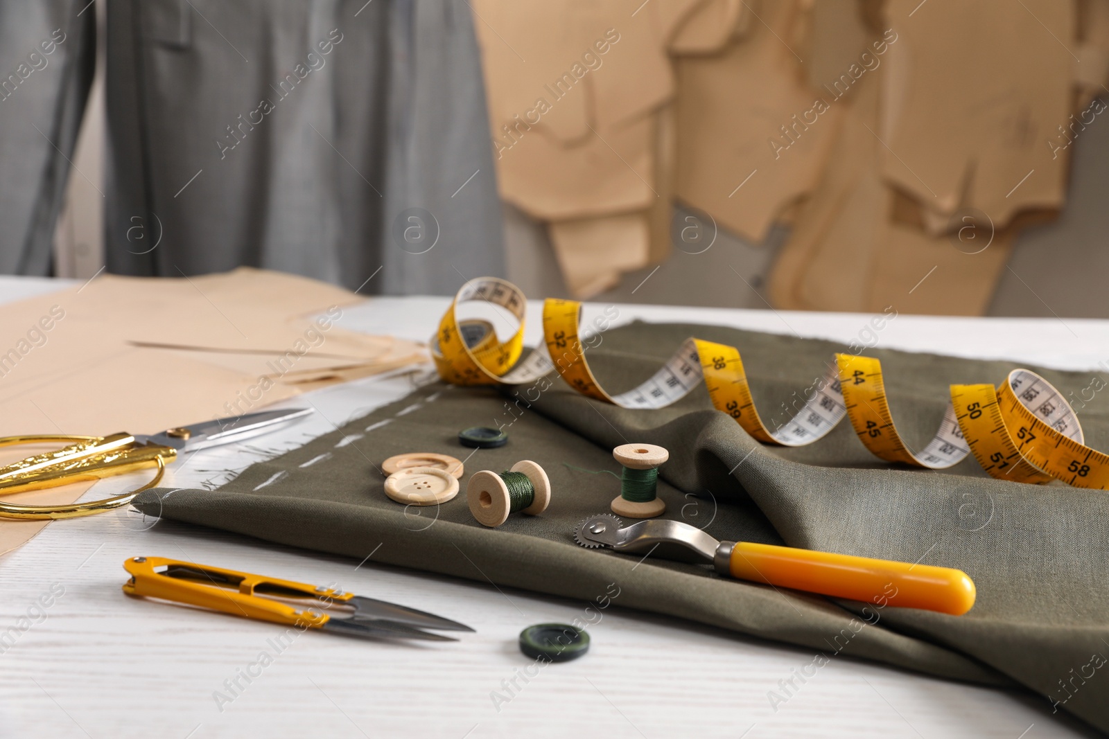 Photo of Set of sewing supplies and accessories with fabric on white wooden table indoors