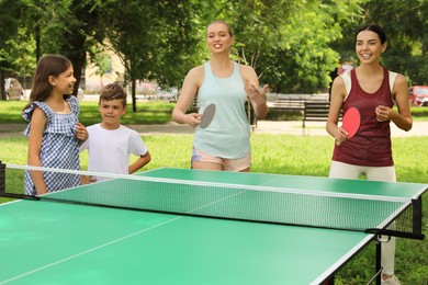 Happy family with children playing ping pong in park