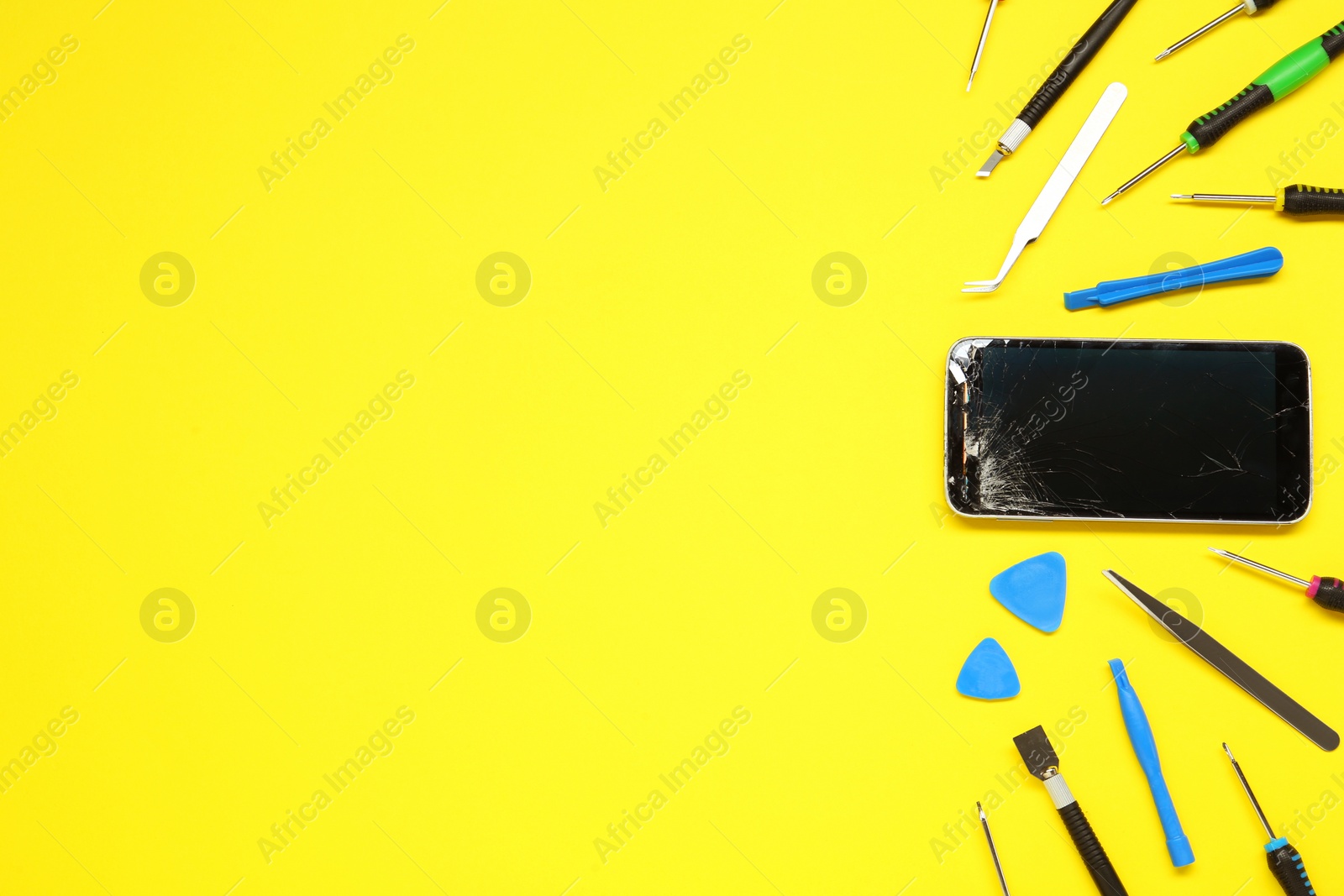 Photo of Damaged smartphone and repair tool set on yellow background, flat lay. Space for text