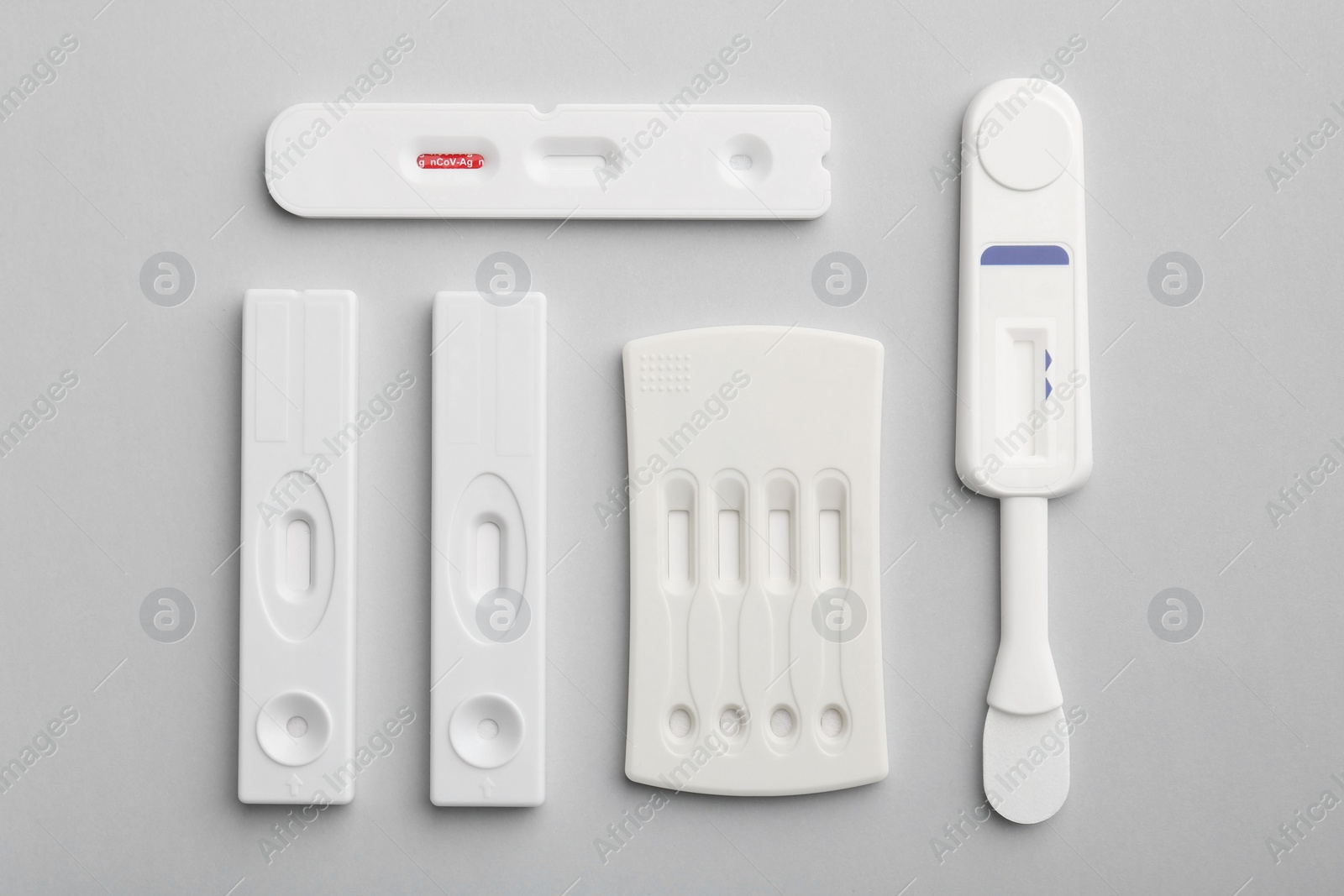 Photo of Different disposable express tests on light grey background, flat lay